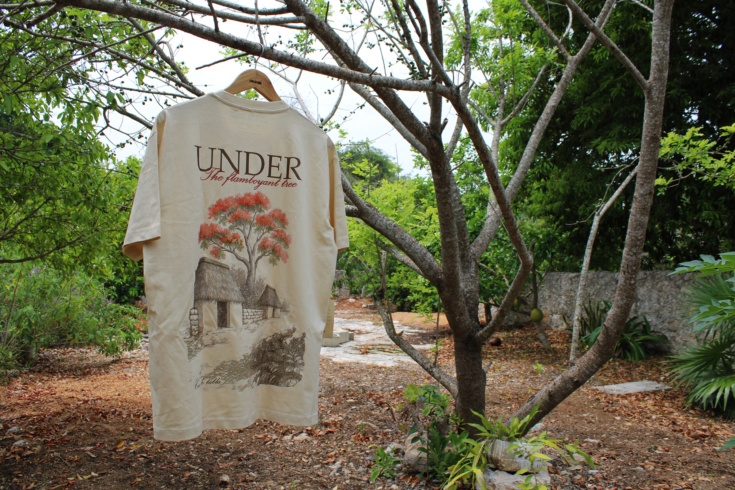 Playera esrampada 'Under the flamboyant tree' colgada frente a un jardín yucateco"